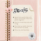 Pink notebook with a decorative paper sheet titled 'goals' on a pink and white striped background.